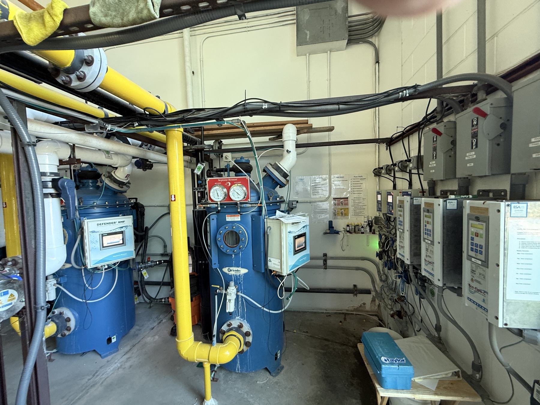 A commercial pool plant room: two regenerative media filters, a controls wall with chemistry controllers and variable-speed drives
